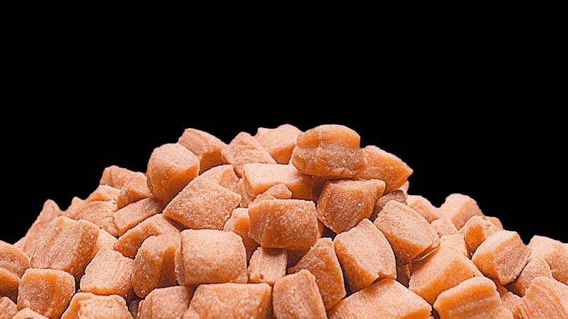 A pile of Mikey's Gourmet Chin-Chin pieces on a black background, showing the golden, crisp texture of the small-batch Nigerian snack.